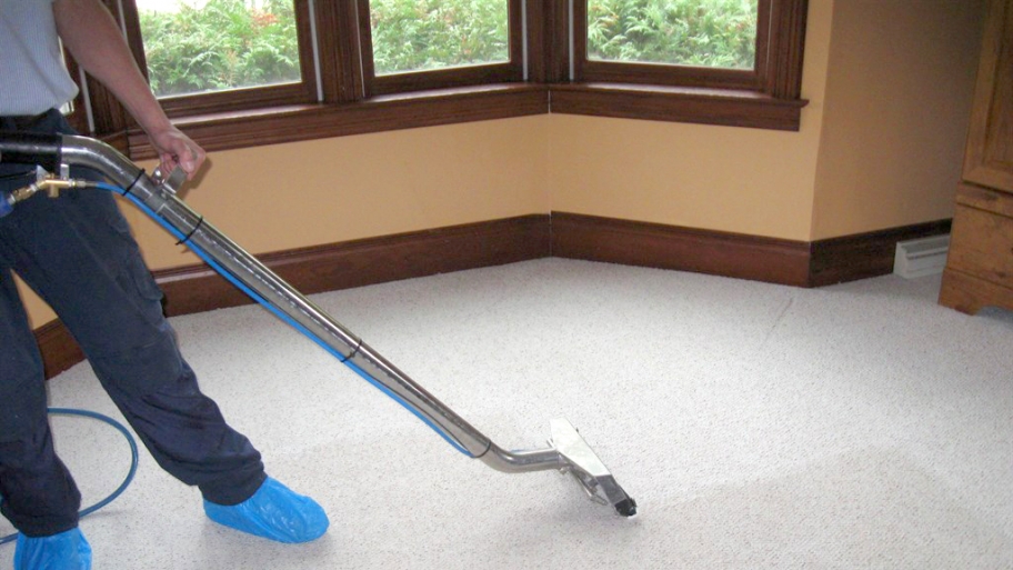 A technician uses a carpet cleaning machine on a carpet